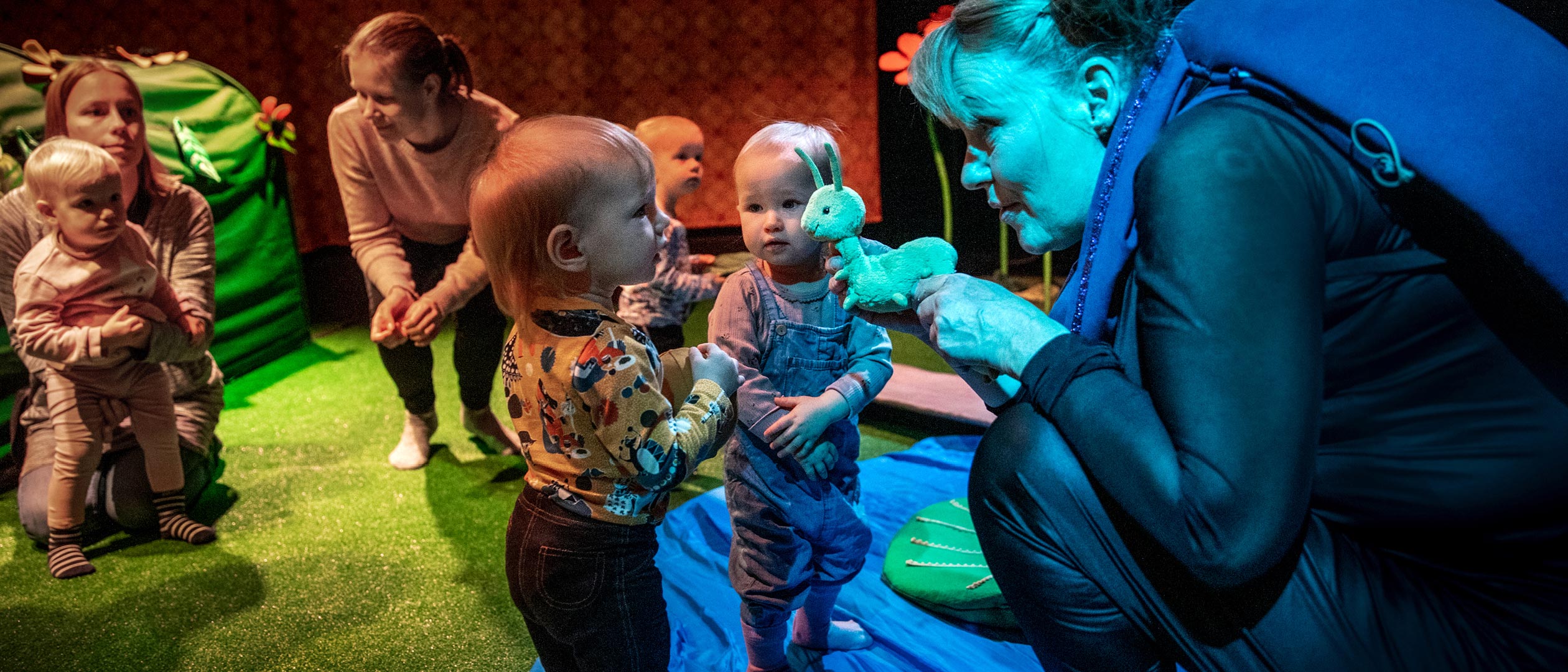 En skådespelare låter barnen runtomkring hälsa på ett mjukisdjur som är en snigel