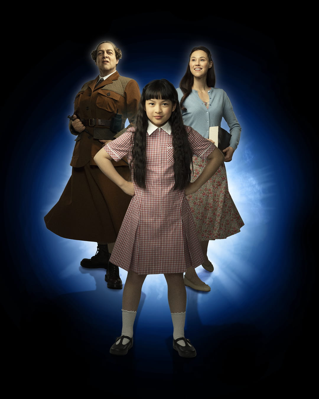 Tyttö Matilda seisoo keskellä. Toisella puolella seisoo ankaran näköinen nainen sauva kädessään. Toisella puolella seisoo nuorempi nainen, hänellä on pehmeä ilme kasvoillaan ja kirja kädessään.